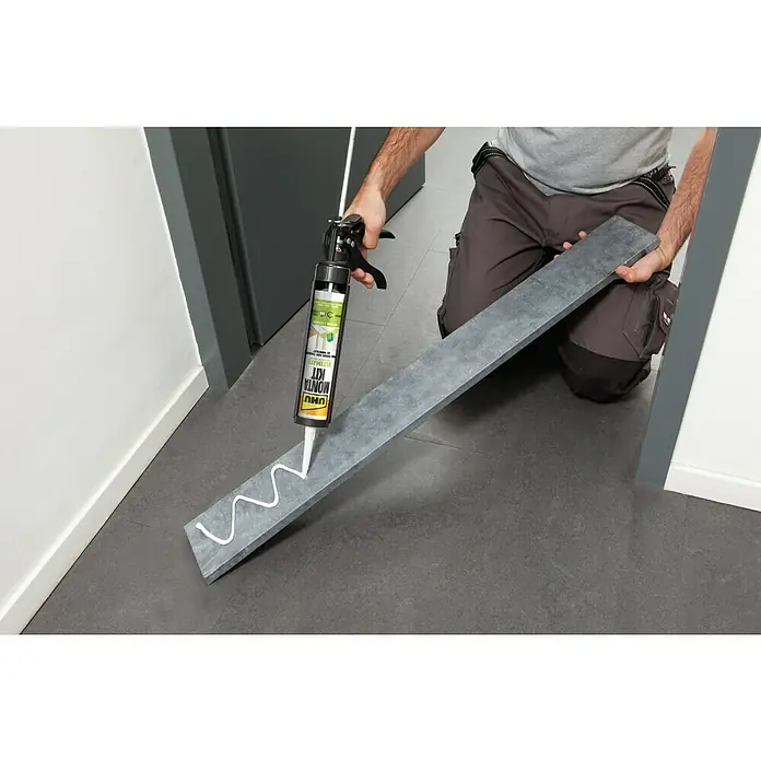 UHU Adhesivo para montaje Montakit Ultimate - 440 g, Cartucho - Un cartucho UHU Montage-Kit se utiliza para aplicar adhesivo a una pieza de trabajo gris sujeta en la mano.