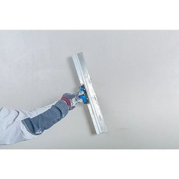 Knauf Rotband Flächenspachtel - 5 kg - Bauarbeiter glättet eine frisch verputzte Wand mit einem Glättspachtel, um eine ebene Oberfläche zu erzielen.
