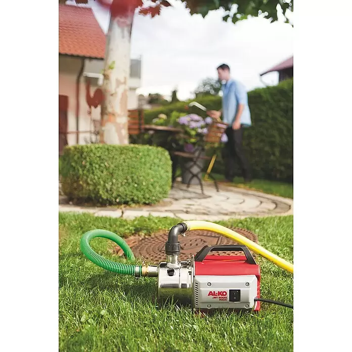 AL-KO Classic Gartenpumpe Jet 3000 Inox - 650 W, Max. Fördermenge: 3.100 l/h - Rot-silberne AL-KO JET 3000 INOX Pumpe mit Schläuchen, zur Gartenbewässerung eingesetzt.