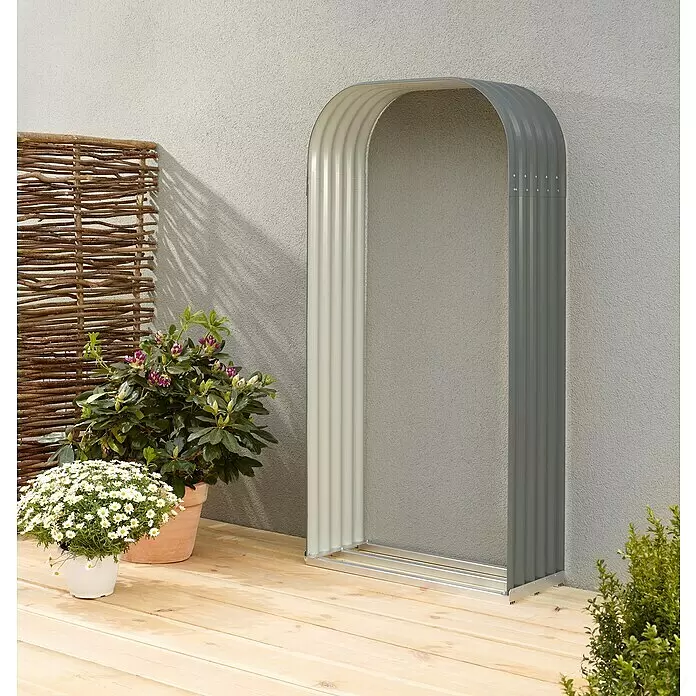 Vitavia Kaminholzregal Lignum 401 - 40 x 99 x 200 cm, Stahl, Granit - Zweifarbiger Wellblech-Gartenbogen auf einer Holzterrasse, neben Topfpflanzen und einem Weidenzaun.