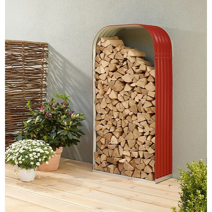 Vitavia Kaminholzregal Lignum 401 - 40 x 99 x 200 cm, Stahl, Rubin - Ein roter Holzstapelständer mit abgerundetem Oberteil, voll mit Holzscheiten, steht auf einer Holzterrasse neben Pflanzen.