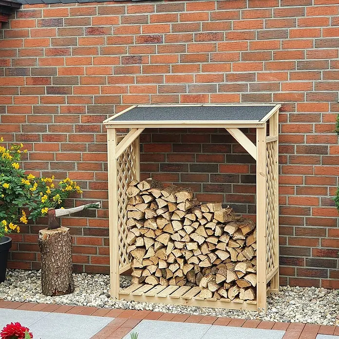 Promadino Kaminholzregal Speyer - 120 x 68 x 148 cm, Holz, Natur, Ohne Wetterschutz - Ein Holzregal aus hellem Holz, gefüllt mit Brennholz, steht vor einer roten Backsteinmauer. Es hat ein schützendes Dach.