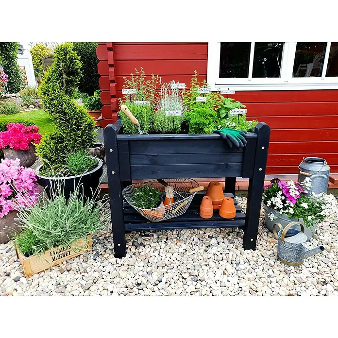 Promadino Kräuterhochbeet - L x B x H: 90 x 60 x 84,5 cm, Anthrazit - Kräutergarten in einem schwarzen Pflanzkasten mit Gartengeräten und Blumen auf einem Kiesweg.