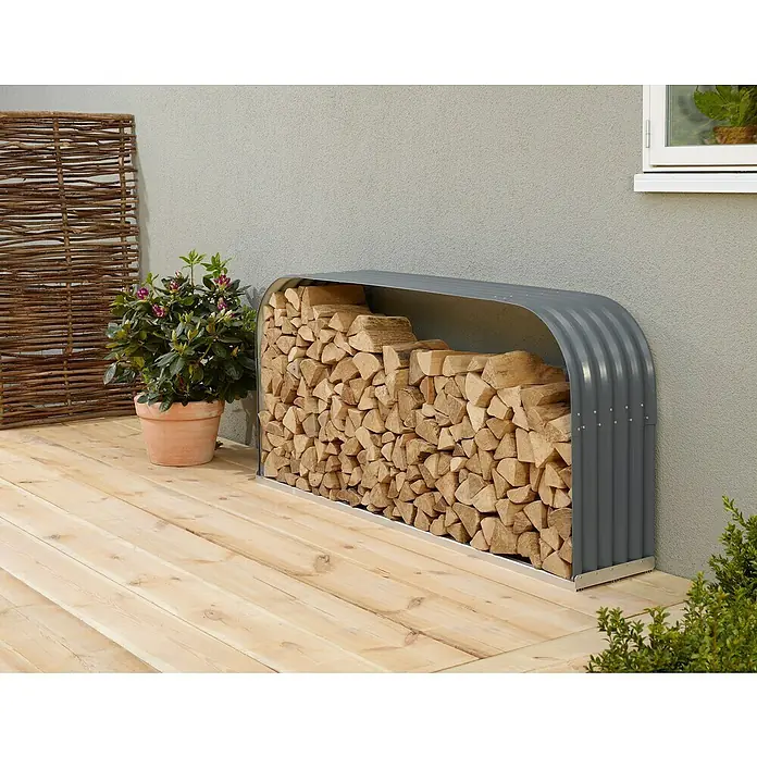 Vitavia Kaminholzregal Lignum 401 - 40 x 210 x 100 cm, Aluminium, Granit - Holzlager im Außenbereich mit grauem Metallgehäuse, gefüllt mit Holzscheiten, neben Topfpflanze auf Holzterrasse.
