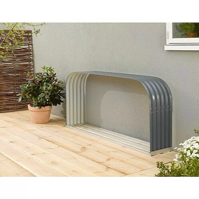 Vitavia Kaminholzregal Lignum 401 - 40 x 210 x 100 cm, Aluminium, Granit - Dunkelgraue, gewellte Metall-Gartenaufbewahrungsbogen auf einer Holzterrasse.