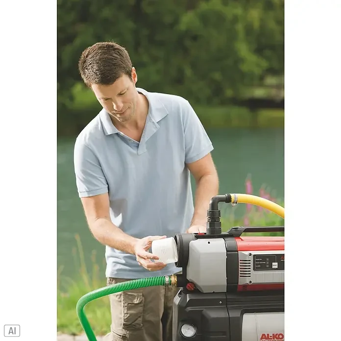 AL-KO Premium Hauswasserautomat 6000/5 - 1.400 W, Max. Fördermenge: 6.000 l/h, Max. Druck: 6 bar - Ein Mann hantiert an einer AL-KO Hauswasserpumpe, die auf einer grünen Wiese steht, mit einem gelben und einem grünen Schlauchanschluss.