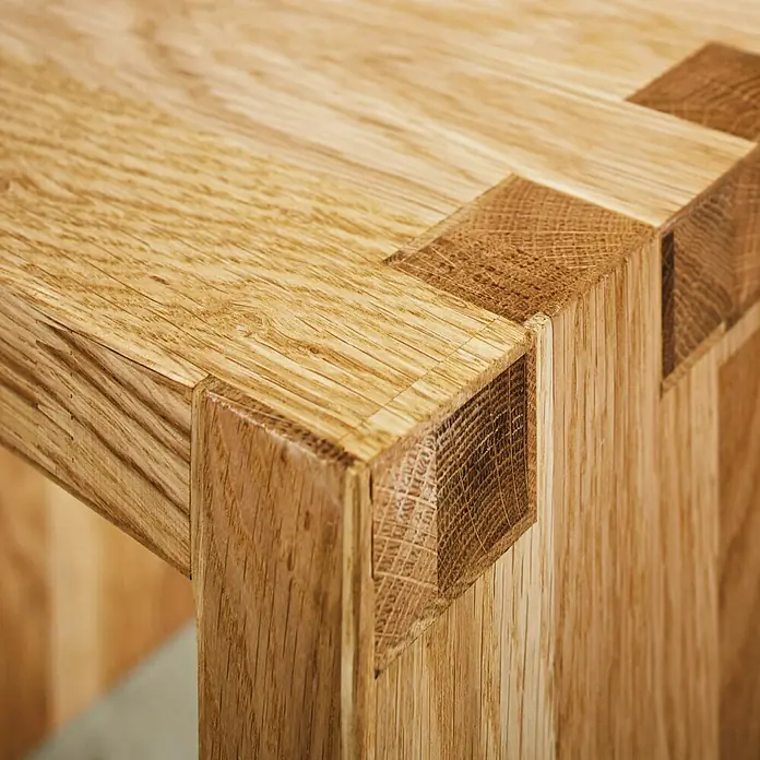 Exclusivholz Aspen Hocker - Eiche, 41,8 x 43 x 43 cm - Detailaufnahme einer Holzarbeit mit einer markanten Eckverbindung, die die natürliche Maserung des Holzes hervorhebt.