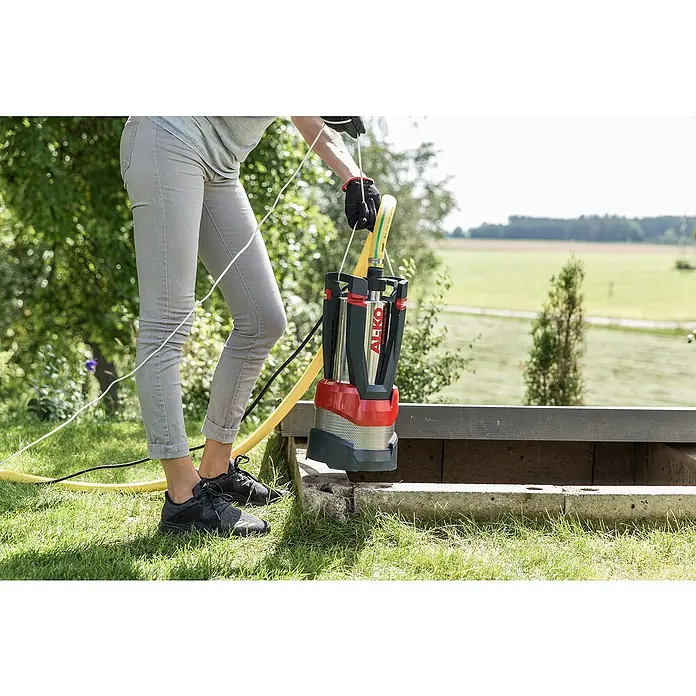 AL-KO Premium Tauchpumpe Dive 6500/34 - 1.000 W, Max. Fördermenge: 6.500 l/h - Eine Person hantiert mit einer AL-KO-Tauchpumpe im Garten, bereit für den Einsatz, um Wasser abzupumpen oder zu bewegen.