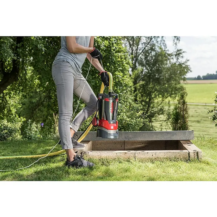 AL-KO Premium Drucktauchpumpe Dive 5600/44 Automatic - 1.200 W, Max. Fördermenge: 5.600 l/h - Frau bedient AL-KO Tauchpumpe auf Rasen. Die Tauchpumpe ist rot/silber und wird zum Entwässern verwendet.
