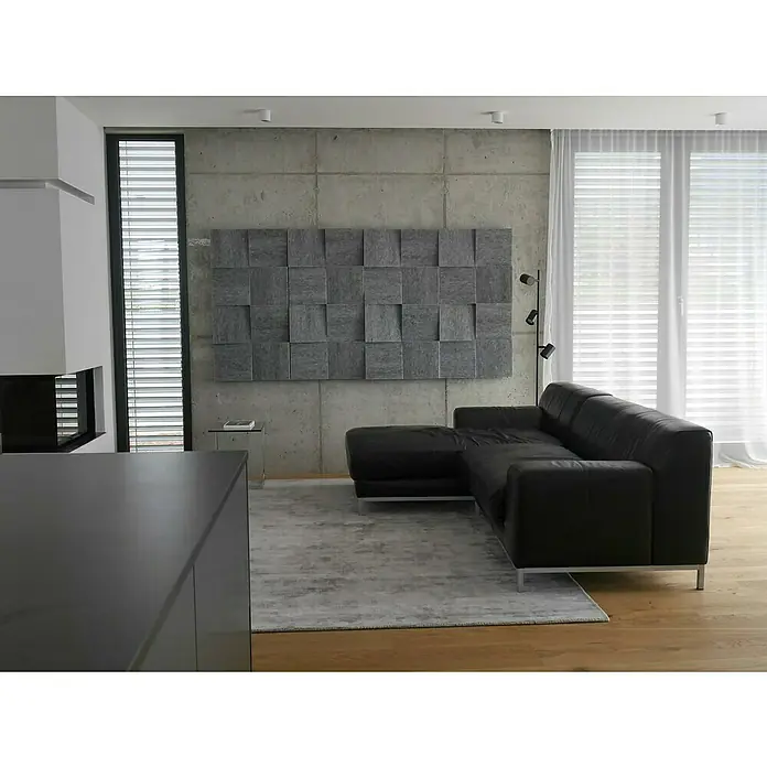 Silenti Akustikpaneel Slope - Hellgrau, 116 cm x 58 cm x 80 mm, 100 % Polyester - Wohnzimmer mit Ledersofa, Akustikpaneel an der Wand und moderner Einrichtung. Das Sofa ist ein markantes Element in dem minimalistischen Raum.