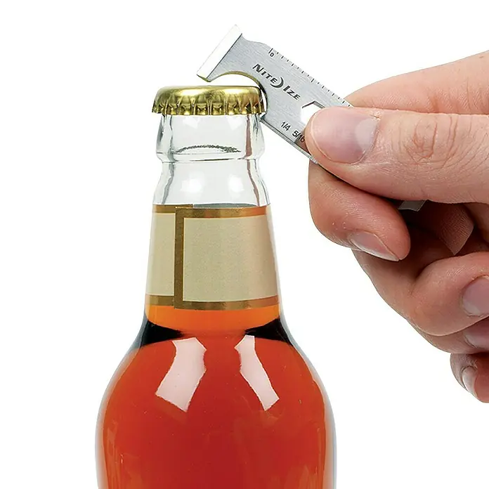 Nite Ize Herramienta multiuso DoohicKey - 6,5 x 1,7 cm, Acero inoxidable, Plateado - Primer plano de un abridor de botellas Nite Ize que se usa para abrir una botella.