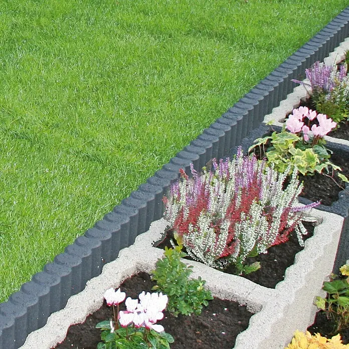 Christoph Palisaden-Randstein - 50 x 6 x 15 cm, Anthrazit - Nahaufnahme einer Blumenrabatte mit Steinbegrenzung, bepflanzt mit bunten Blumen und grünen Pflanzen.