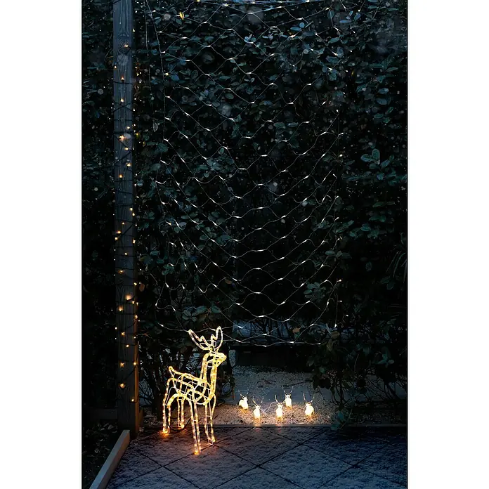 Konstsmide LED-Weihnachtsdekoleuchte LED Acryl - 4 m x 13 cm x 19 cm, Weiß, Netzbetrieben, LED - Stimmungsvolle Gartendekoration mit einem leuchtenden Rentier und einem Netz aus Lichterketten vor einer grünen Hecke.