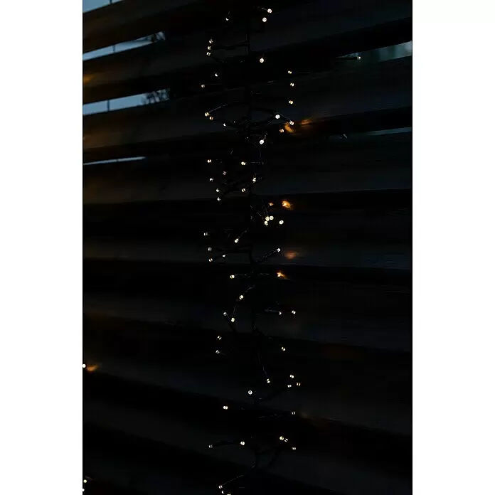 Tween Light LED-Clusterlichterkette - Außen, Länge: 8,15 m, 768 Stk., Netzbetrieben, Lichtfarbe: Warmweiß - Warmweiße LED-Cluster-Lichterkette vor dunklem Lattenzaun aus Holz.
