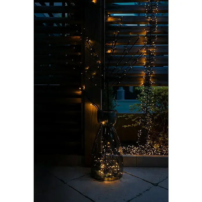 Tween Light Cadena de luces LED - Para exterior, Largo: 8,15 m, 768 ud., Funcionamiento en red, Color de luz: Blanco cálido - Decoración atmosférica: Un jarrón de vidrio con ramas iluminadas y luces crea una luz cálida y acogedora en la habitación.