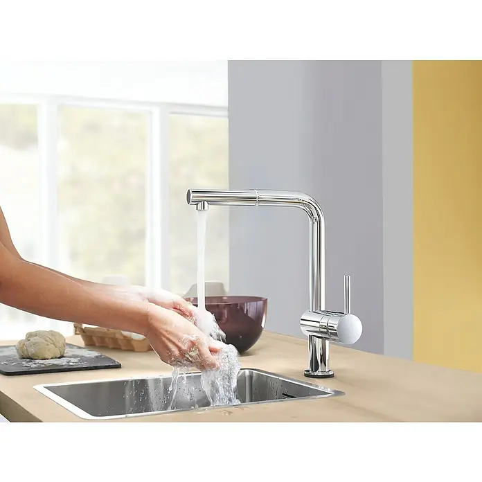 Grohe Spültischarmatur Minta Touch - Chrom, Glänzend - Eine Person wäscht ihre Hände unter einem modernen Chrom-Küchenhahn. Der Wasserhahn ist elegant und funktional gestaltet.