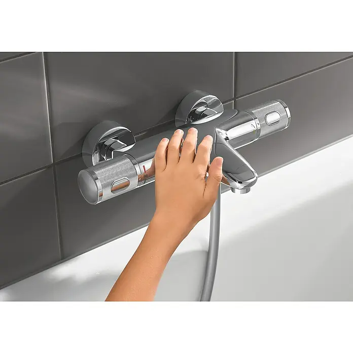Grohe Precision Feel Wannenthermostat - Chrom, Glänzend - Bild einer Armatur mit einer Hand, die sie bedient. Die Armatur ist aus Chrom und hat ein modernes Design.