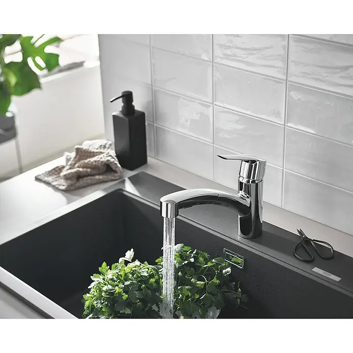 Grohe QuickFix Spültischarmatur Start - Chrom, Ausziehbar, Glänzend - Nahaufnahme einer modernen Küchenspüle mit Armatur, frischer Petersilie und einer schwarzen Seifenpumpe vor weißen Fliesen.