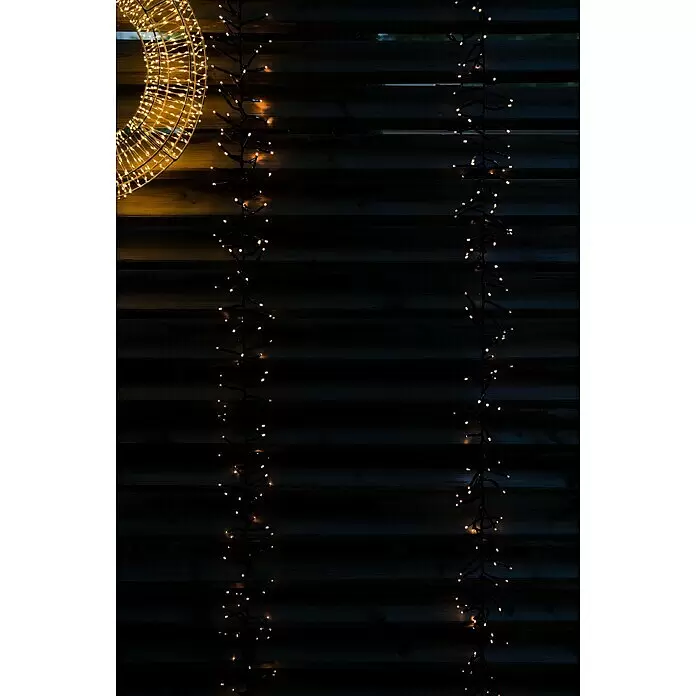 Tween Light LED-Clusterlichterkette - Außen, Länge: 8,15 m, 768 Stk., Netzbetrieben, Lichtfarbe: Warmweiß - Warmweiße Cluster-Weihnachtsbeleuchtung und eine große runde Lichtdekoration beleuchten einen dunklen Holzzaun.