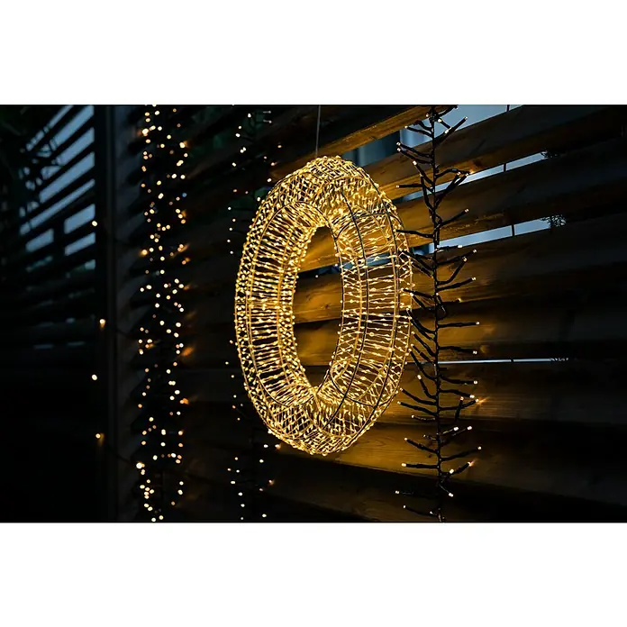 Tween Light LED-Clusterlichterkette - Außen, Länge: 8,15 m, 768 Stk., Netzbetrieben, Lichtfarbe: Warmweiß - Außenansicht eines leuchtenden, runden LED-Weihnachtsdekorationsobjekts, das an einer Holzwand hängt und festliche Stimmung verbreitet.