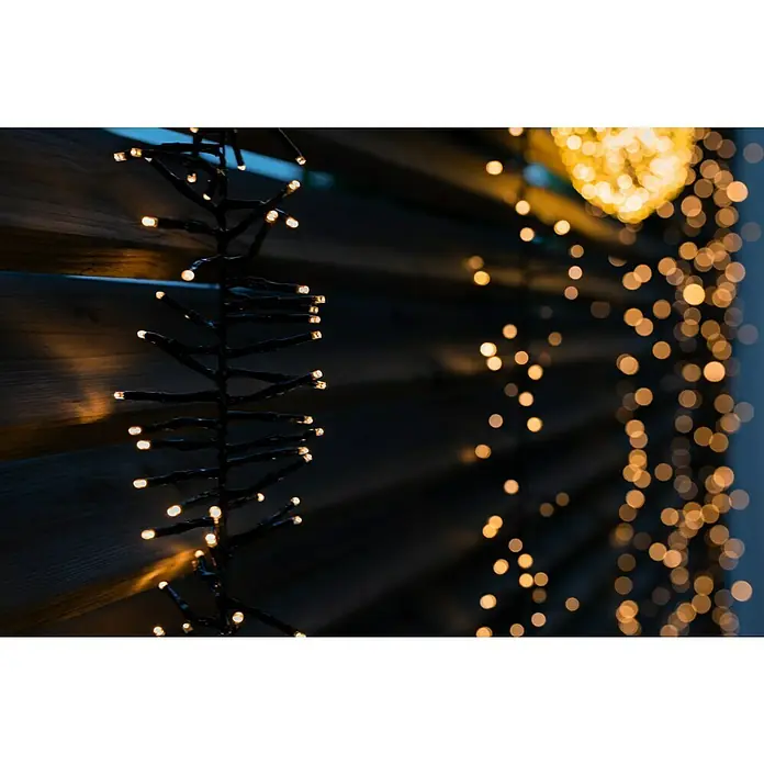 Tween Light Cadena de luces LED - Para exterior, Largo: 8,15 m, 768 ud., Funcionamiento en red, Color de luz: Blanco cálido - Cadena de luces con luces blancas cálidas que crean un ambiente acogedor colgadas frente a una superficie de madera oscura.