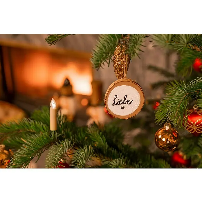 Christbaumschmuck Zapfen - Gold, Kunststoff, 6 Stk. - Weihnachtliche Nahaufnahme eines Baumschmuckstücks mit der Aufschrift "Liebe" vor einem warmen Kamin.