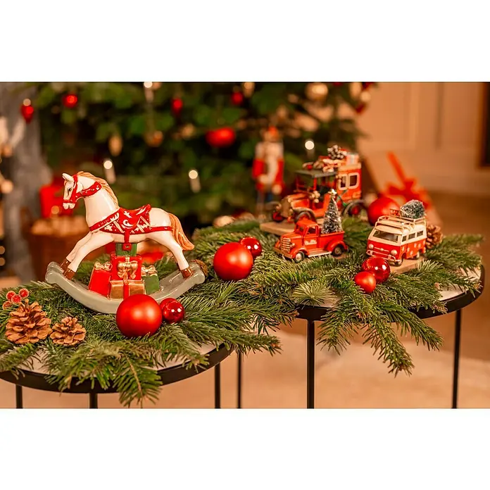 Dekofigur Weihnachtsbus - L x B x H: 12 x 5 x 10 cm, Metall, X-Mas - Weihnachtliches Stillleben mit einem Schaukelpferd, Spielzeugautos, Christbaumkugeln und Tannenzweigen auf einem Tisch vor einem Weihnachtsbaum.