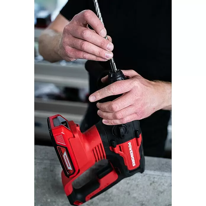 Powerworks Akku-Bohrhammer PD24SDS2 - 24 V, Ohne Akku, 2 J - Roter und schwarzer Powerworks Bohrhammer, von Händen gehalten, während ein Bohrer in das Futter eingesetzt wird.