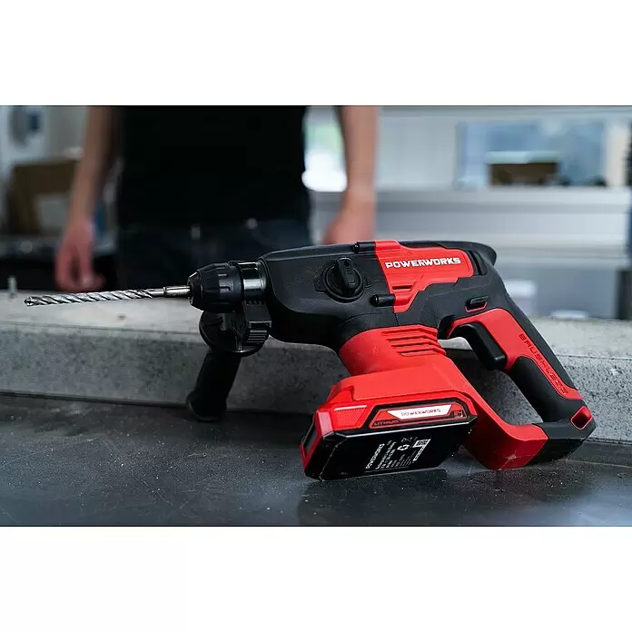 Powerworks Akku-Bohrhammer PD24SDS2 - 24 V, Ohne Akku, 2 J - Roter und schwarzer Akku-Bohrhammer mit Bohrer, auf einer Werkbank liegend.