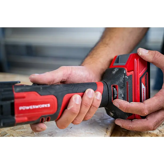 Powerworks Akku-Multifunktionswerkzeug P24MT - 24 V, Ohne Akku - Ein rotes und schwarzes Powerworks-Elektrowerkzeug wird von Händen gehalten, wobei der Fokus auf den Details des Werkzeugs liegt.