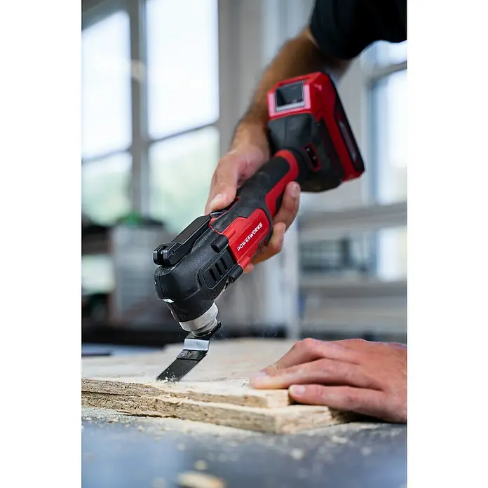 Powerworks Akku-Multifunktionswerkzeug P24MT - 24 V, Ohne Akku - Nahaufnahme eines Powerworks-Multifunktionswerkzeugs, das ein Holzstück bearbeitet, wobei die rote und schwarze Bauweise des Werkzeugs hervorgehoben wird.