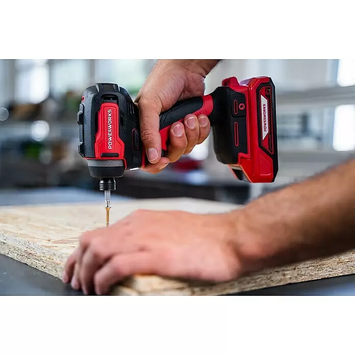 Powerworks Akku-Schlagschrauber PD24ID220 - 24 V, Ohne Akku, 220 Nm - Rot-schwarzer PowerWorks 24V Schlagschrauber, der von einer Hand in eine Holzplatte geschraubt wird.