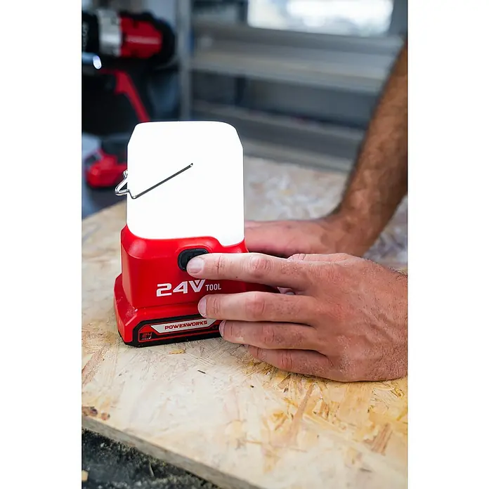 Powerworks LED-Arbeitsleuchte P24LA500 - 24 V, Ohne Akku, 500 lm - Ein rotes Powerworks 24V Werkzeug mit weißem Licht wird von einer Person auf einem Holztisch bedient.