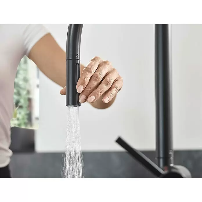 Hansgrohe Spültischarmatur Talis M54 210 - Anzahl Strahlarten: 2 Stk., Schwarz, Matt - Hand hält schwarzen ausziehbaren Küchenarmatur-Brausekopf mit fließendem Wasser.
