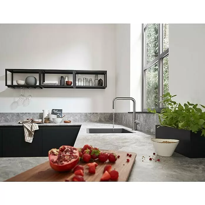 Hansgrohe Spültischarmatur Talis M54 U 220 - Edelstahl, Matt - Moderner, metallischer Küchenarmatur mit fließendem Wasser in ein dunkles Spülbecken, in einer minimalistischen Küche.