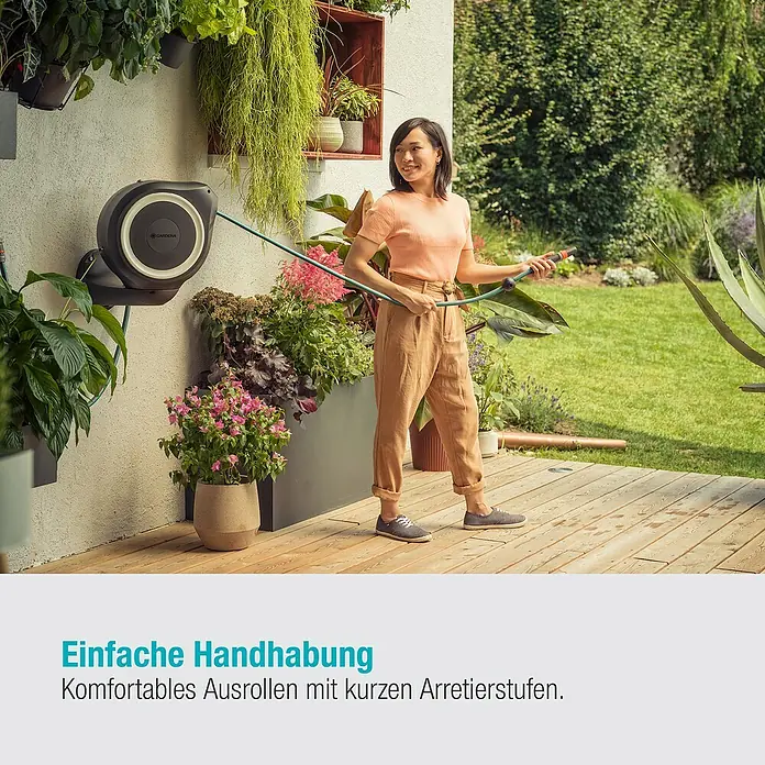 Gardena Wand-Schlauchbox RollUp S - Schlauchlänge: 15 m - Frau gießt Blumen mit einer Gardena Wand-Schlauchbox 35 roll-up automatic, die an der Wand befestigt ist.