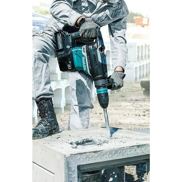Makita XGT 40V max. Akku-Kombihammer HR005GZ01 - 8 J, 40 V, Ohne Akku - Ein Bauarbeiter benutzt einen Makita Akku-Bohrhammer, um ein Loch in einen Betonblock zu bohren. Der Bohrhammer ist blaugrün und schwarz.