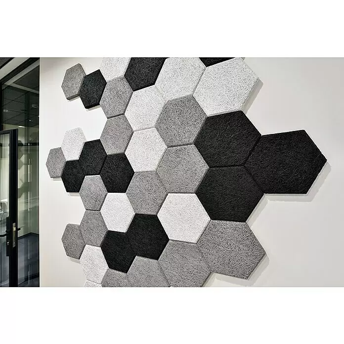 FibroTech Akustikplatte Hexagon - Weiß, 250 x 289 x 25 mm, 18 Stk., 0,972 m² - Sechseckige Akustikpaneele in Schwarz, Weiß und Grau aus faserigem, schallabsorbierendem Material an einer Wand.