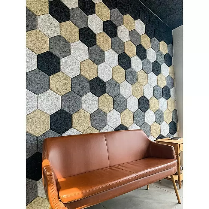 FibroTech Placa acústica - Gris, 250 x 289 x 25 mm, 18 ud., 0,972 m² - Paneles acústicos hexagonales negros, blancos, grises y beis, montados en la pared sobre un sofá marrón.