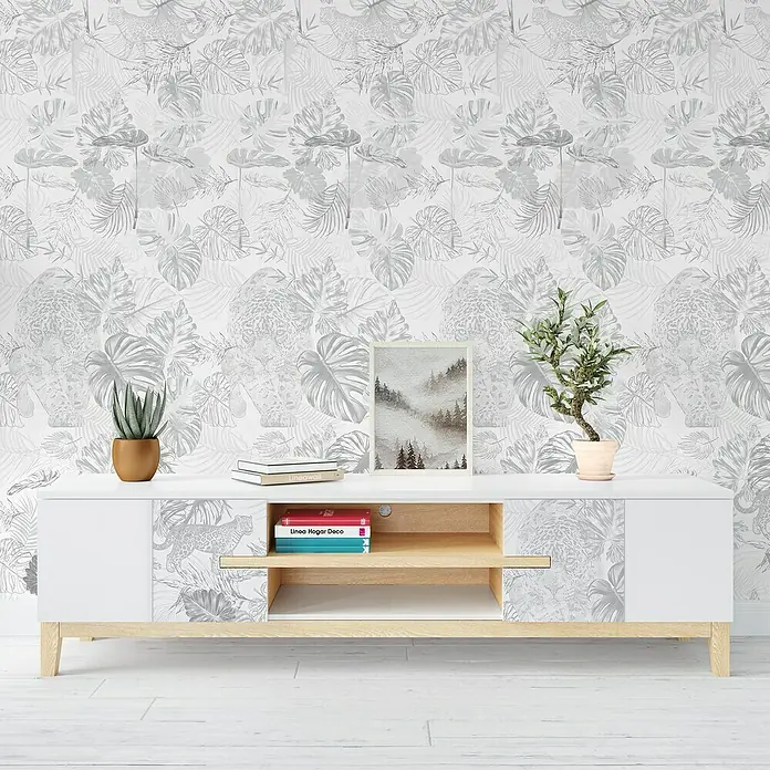 Papel pintado vinílico adhesivo Lineawall - Jaguar, 90 cm x 2,8 m - Un aparador blanco con un estampado botánico, decorado con plantas, libros y una imagen enmarcada, sobre un papel tapiz a juego.