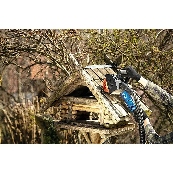 Scheppach Nylon-Scheibenbürste - Durchmesser: 125 mm, Passend für: Scheppach Multischleifer MRS1300 - Eine Person reinigt ein Vogelhaus mit einer elektrischen Bürste, um es sauber und einladend für gefiederte Freunde zu halten.