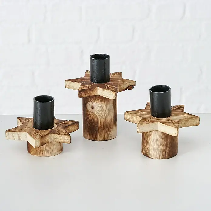 Kerzenhalter Viby Stern - Ø x H: 9 x 11 cm, Holz - Drei Holzkerzenhalter mit Sternenfuß und schwarzem Metalleinsatz für Stabkerzen auf einem weißen Tisch vor einer weißen Wand.