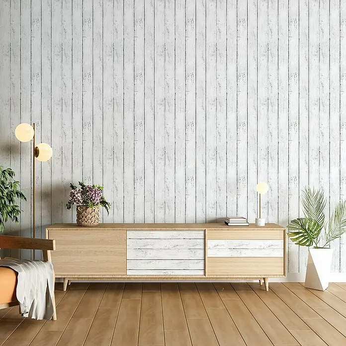 Papel pintado vinílico adhesivo Lineawall - Tablero blanco, 90 cm x 2,8 m - Un salón moderno con un mueble de madera clara, una lámpara de pie y plantas sobre un fondo de pared de madera encalada.