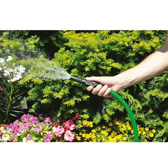 Schlauch-Set Basic - 25 m, Schlauchdurchmesser: 19 mm - Gartenszene mit einer Person, die einen grünen Gartenschlauch hält, der Wasser auf bunte Blumen und grüne Pflanzen sprüht.