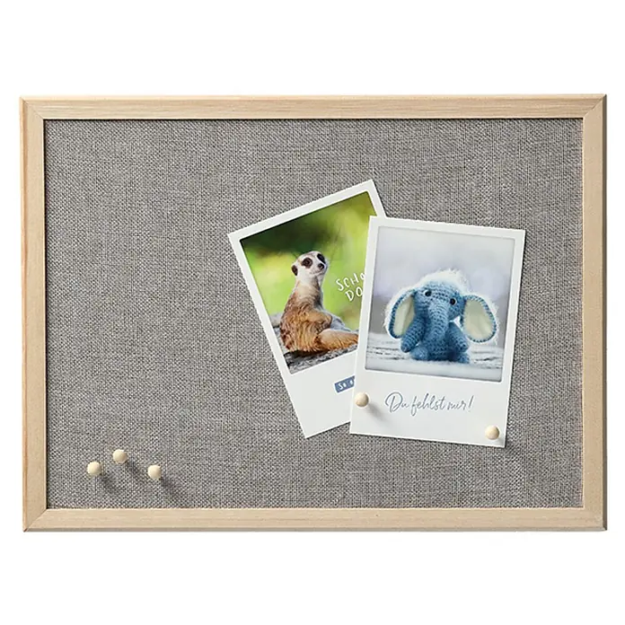 Zeller Present Pinnwand - 40 x 30 cm, Holz - Eine Pinnwand mit hellem Holzrahmen und grauem Stoffbezug. Darauf sind zwei Fotos und ein paar hölzerne Reißnägel befestigt.