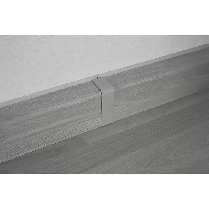 Marley Übergangskappe - Esche Weiß - Graue Sockelleiste in Holzoptik mit hellem Verbindungsstück, das zwei Abschnitte verbindet.