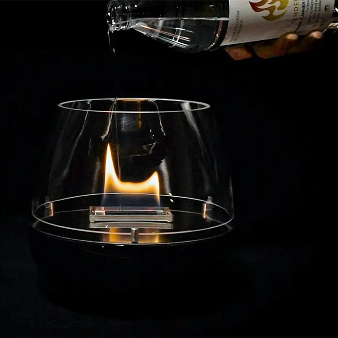 Tenderflame Spezialbrennstoff - 1 l - Tischkamin wird mit Brennstoff befüllt. Dekorative Feuerstelle für Innenräume mit schützendem Glasaufsatz auf dunklem Untergrund.