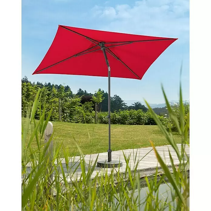 Schneider Classic Marktschirm Sevilla - Rot, Bespannungsmaß (L x B): 240 x 140 cm - Roter rechteckiger Gartenschirm mit dunkelgrauem Mast und Fuß steht auf einer Holzterrasse am Wasser im sonnigen Garten.