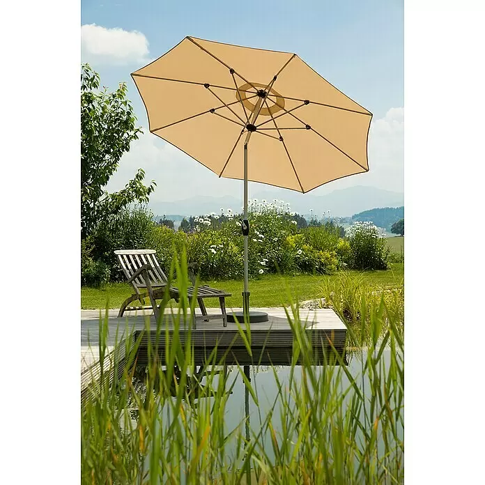 Schneider Classic Marktschirm rund Venedig - Natur, Durchmesser Bespannung: 270 cm - Beigefarbener Gartenschirm offen, spendet Schatten für einen Holzliegestuhl auf einer Terrasse an einem Naturteich in einem hellen, grünen Garten.