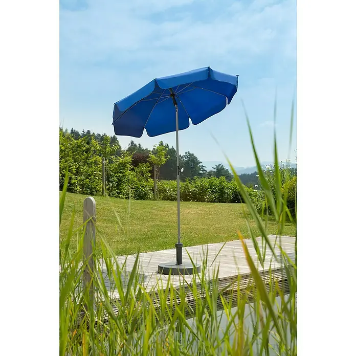 Schneider Classic Marktschirm rund LocarnoRoyalblau, Durchmesser Bespannung: 150 cm - Ein blauer Sonnenschirm steht auf einer Holzterrasse, umgeben von Grün. Der Schirm bietet Schatten an einem sonnigen Tag im Freien.